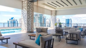 Ein moderner Lounge-Bereich Blick auf einen Pool, mit Sofas und Sesseln möbliert, mit Blick auf die Stadt durch große Fenster.