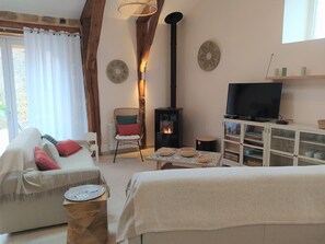 Ein gemütliches Wohnzimmer mit einer Couch, einem Sessel, einem Fernseher, einem Kamin und einer Vitrine.