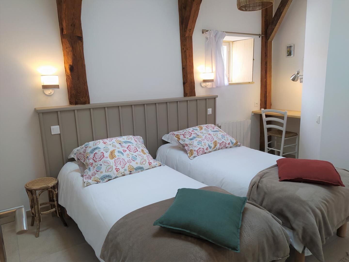Une chambre avec deux lits, un petit tabouret, une chaise, un miroir et un radiateur.