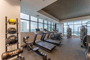 Ein Fitnessstudio mit Laufbändern, Kraftgeräten und Übungsbällen, ausgestattet mit großen Fenstern und Blick auf die Stadt.