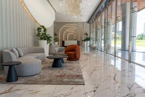 Eine moderne Lobby mit einer gebogenen Couch, einem runden Couchtisch und einer Zimmerpflanze.