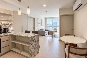 A modern kitchen with marble countertops, a dining area with a round table, and a living space with a sofa and chairs. - 2-Bedroom Coastal View Apartment in Panama (Panamá)