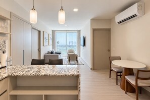 Eine moderne Küche mit Marmorarbeitsplatte, ein Essbereich mit rundem Tisch und ein Wohnbereich mit Sofa und Sesseln.