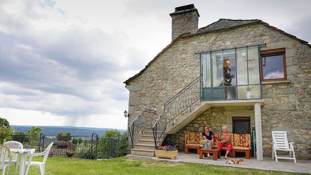 Ein Steinhaus mit Balkon, Sitzgelegenheit im Freien und Blick auf die Landschaft.
