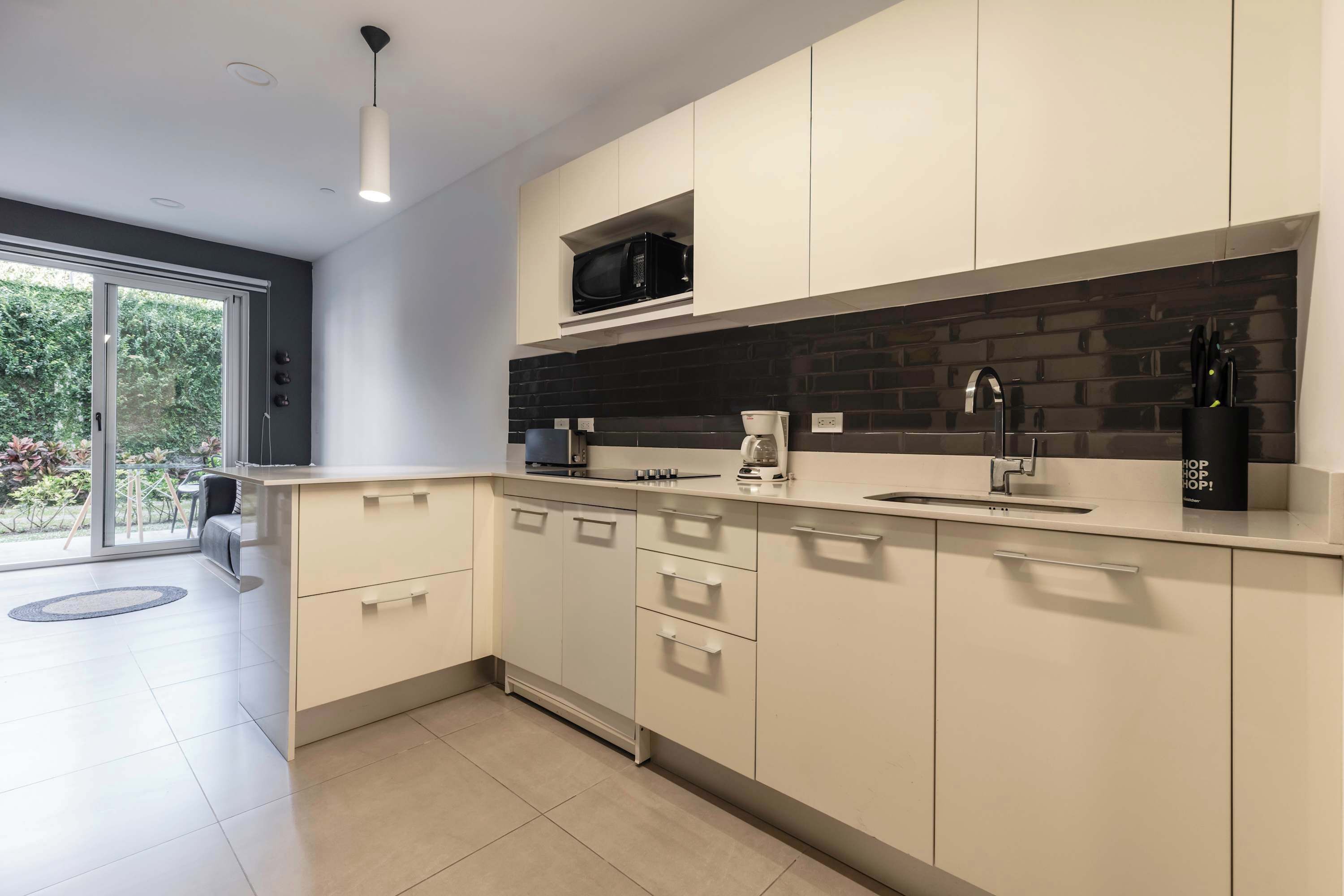Une cuisine moderne avec des meubles blancs, un pare-feu noir et un four à micro-ondes encastré.