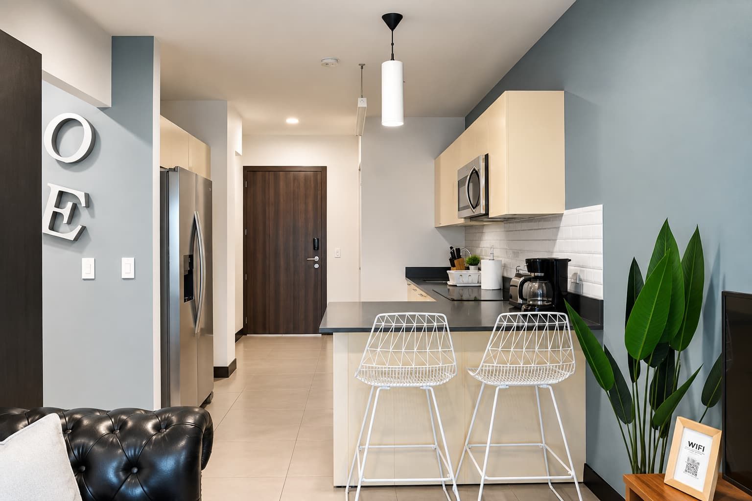 A modern kitchen with a microwave, stove, and bar stools.