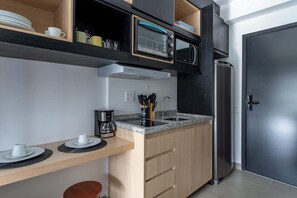 A compact kitchen with a microwave, toaster oven, and refrigerator. - Serviced Studio in São Paulo with City Views (São Paulo)
