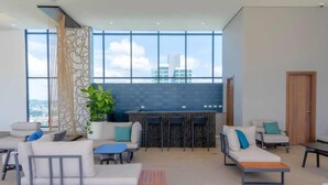 Ein moderner Lounge-Bereich mit Sitzgelegenheiten, einer Bar und großen Fenstern mit Blick auf die Stadt.