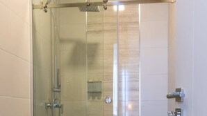 A modern bathroom with a glass-enclosed shower, a toilet, and a sink. - Modern 2-Bedroom Suite in Panama (Panamá)