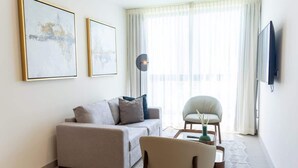 A modern living room with a sofa, armchair, coffee table, floor lamp, and artwork on the wall. - Modern 2-Bedroom Suite in Panama (Panamá)