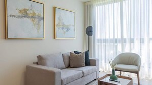 A living room with a sofa, a chair, a coffee table, and two framed artworks on the wall. - Modern 2-Bedroom Suite in Panama (Panamá)