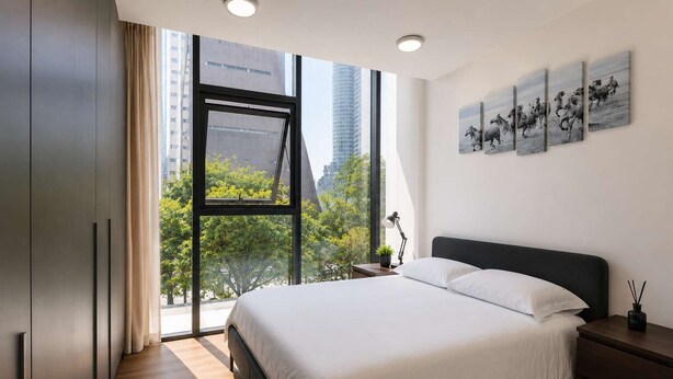 Una camera da letto moderna con un'ampia finestra, un letto, un comodino e un'opera d'arte appesa al muro.