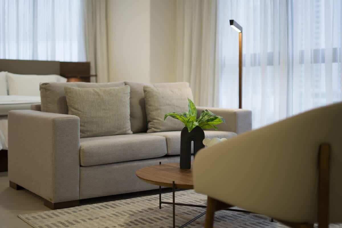 Ein modernes Hotelzimmer mit einer Couch, einem kleinen runden Tisch und einem Blumentopf.