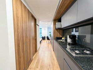 A narrow kitchen with a stove, microwave, and cabinets. - Serviced Studio in Mexico City (Mexico City)