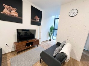 A modern living room with a flat-screen TV, a grey sofa, a patterned rug, and artwork on the walls. - Serviced Studio in Mexico City (Mexico City)
