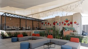 A modern outdoor seating area with sofas and ottomans, a bar area, and decorative wall art.