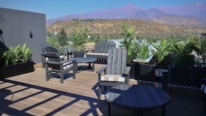 An outdoor patio with wooden furniture, a round table, and potted plants.