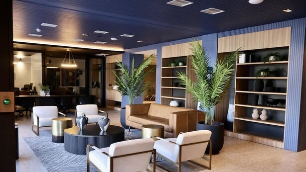 A modern lobby with a sofa, chairs, a coffee table, and potted plants.