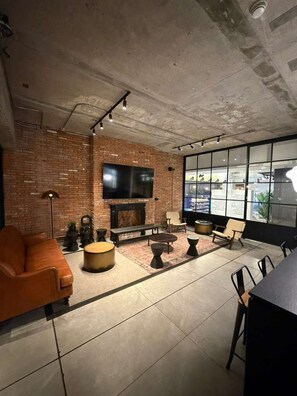 Ein modernes Wohnzimmer mit Backsteinwand, Flachbildfernseher, Kamin und großem Fenster.