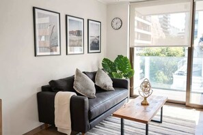 Ein modernes Wohnzimmer mit einer schwarzen Couch, einem Couchtisch und gerahmten Bildern an der Wand.