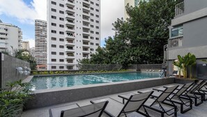 A rooftop pool with lounge chairs, surrounded by high-rise buildings and greenery. - Furnished Studio in São Paulo with City Views (São Paulo)