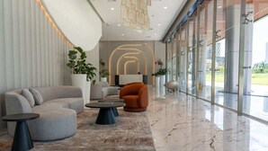 Un hall d’entrée moderne avec un canapé incurvé, une table basse ronde et une plante en pot.