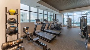 Une salle de sport équipée de tapis de course, d’appareils de musculation et de ballons d’exercice.