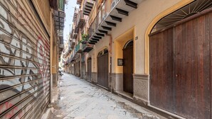 Une rue étroite, bordée de boutiques fermées et d’immeubles dotés de balcons.