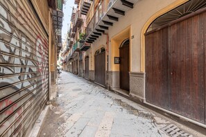 A narrow street with closed shops and buildings with balconies. - Avio apartment (PALERMO)