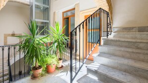 Un escalier avec une rampe noire menant à une pièce dont la porte est en bois.