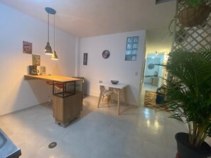 Una cocina moderna con encimera de madera, luces colgantes y un comedor con una mesa pequeña y sillas.