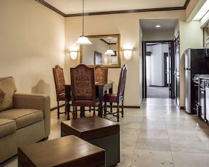 A hotel room with a dining area, a sofa, a coffee table, and a kitchen area with a refrigerator. - Hilton Vacation Club St. Augustine (St. Augustine)