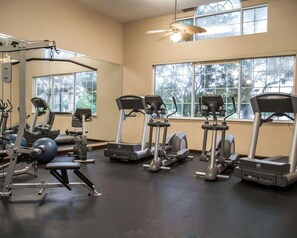 Une salle de sport équipée de tapis de course, de vélos elliptiques et de matériel de musculation.