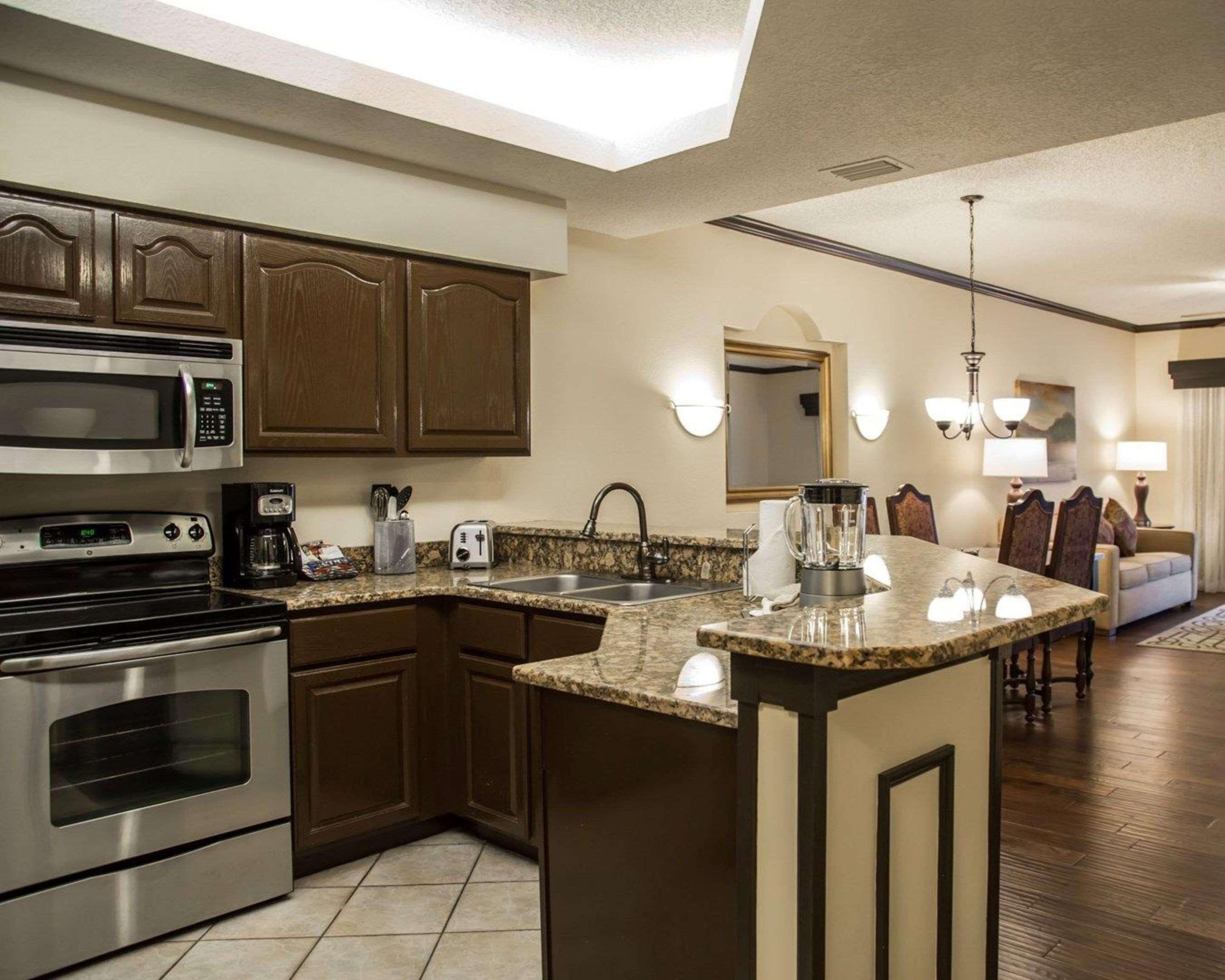 A modern kitchen with built-in appliances, a granite countertop island, and a dining area with a chandelier.