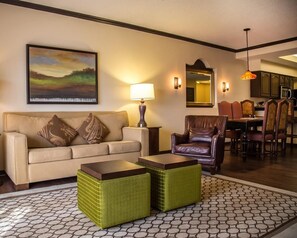 A living room with a sofa, armchairs, a coffee table, a dining area with chairs, a lamp, and a painting on the wall. - Hilton Vacation Club St. Augustine (St. Augustine)