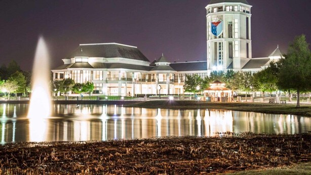 A large building with a prominent tower, a fountain in the foreground, and a calm body of water reflecting the structure. - Hilton Vacation Club St. Augustine (St. Augustine)