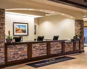 A reception desk with a stone facade, framed pictures, and a check-in sign. - Hilton Vacation Club St. Augustine (St. Augustine)