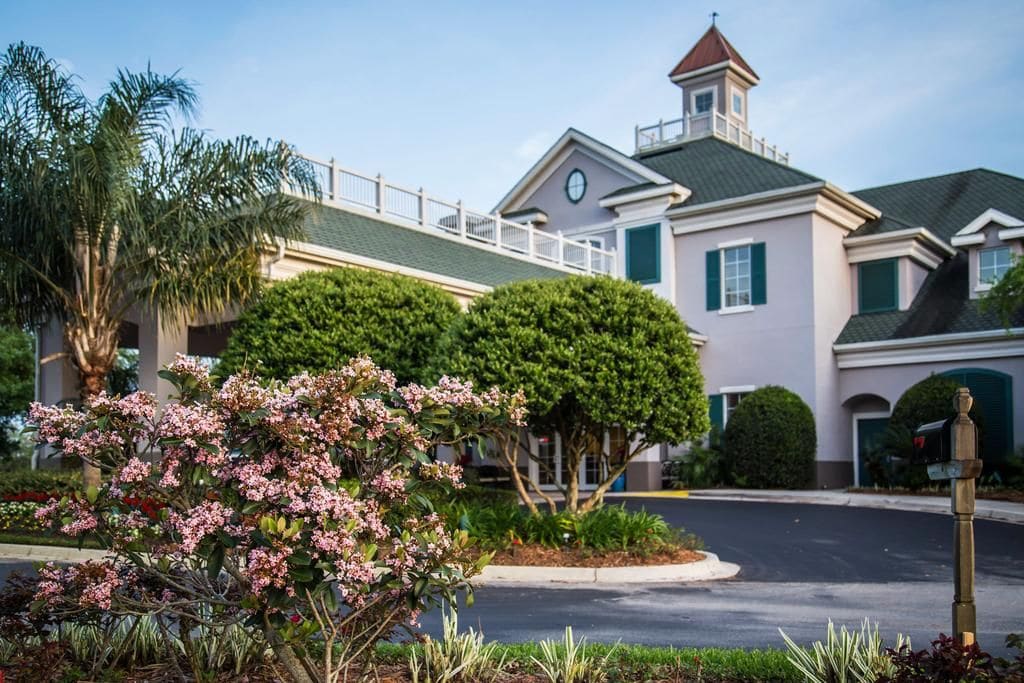 A residential building with a prominent clock tower, a covered walkway, and well-maintained landscaping.
