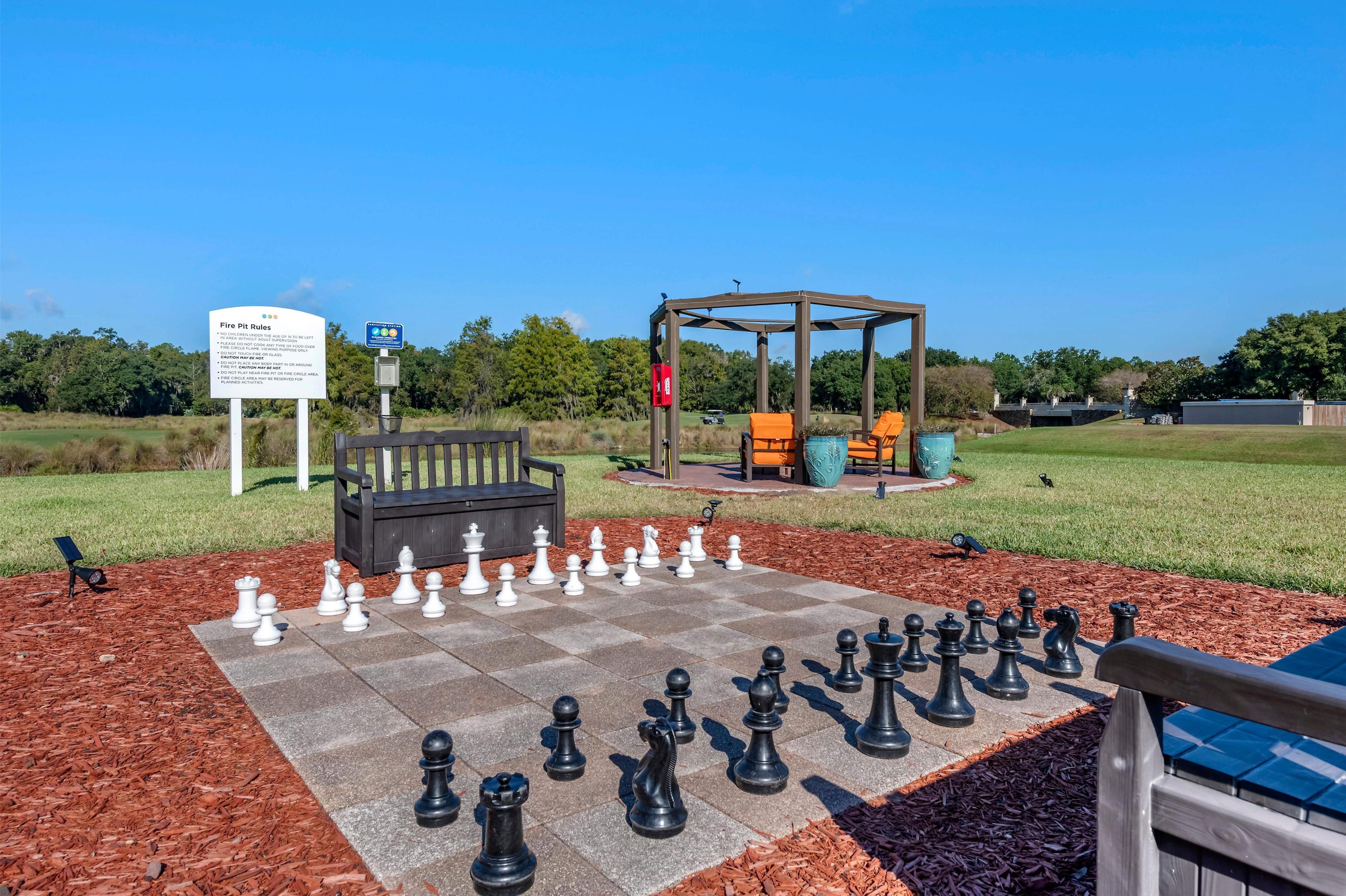 A chessboard set up outdoors with a gazebo and a sign in the background.