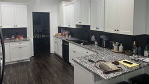 Une cuisine moderne avec des meubles blancs, un plan de travail en granit et un parquet en bois foncé.