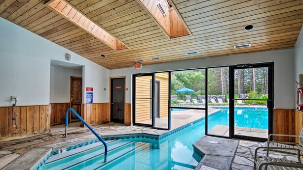 Una piscina interior con techo de madera, vistas despejadas al exterior y un cartel que indica 'no buceo'.