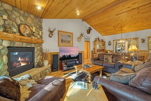 Ein gemütliches Wohnzimmer mit Kamin, Ledersofas, einer Steinwand und montierten Tierköpfen.
