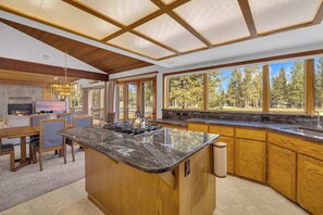A kitchen with a large island, wooden cabinets, and a view of trees. - AC, View of Golf Course, Ping Pong, by North Store (Sunriver)
