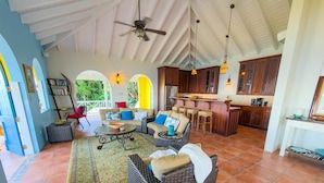 A spacious living area with wicker furniture, a dining area, and a kitchen with wooden cabinets.