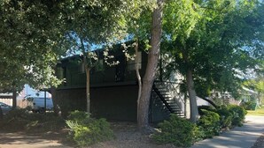 A residential building with a staircase leading to an upper level, surrounded by trees and a sidewalk. - Cozy 1-bedroom condo in enjoyable Chico with AC (Chico)