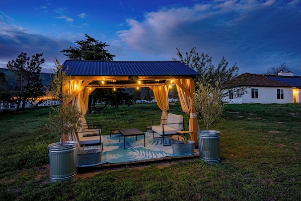A gazebo with string lights, outdoor seating, and potted plants. - Pet-friendly RV stay at a horse ranch in a fenced 5 acre lot in the hills (Acton)