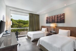 A hotel room with two beds, a desk, a TV, and a balcony with a view of greenery. - PALMERAS DEL CARIBE - STUDIOS and SUITES (Punta Cana)