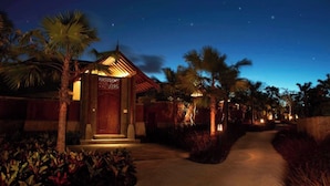 A pathway leading to a building with a traditional design, surrounded by palm trees and plants. - PALMERAS DEL CARIBE - STUDIOS and SUITES (Punta Cana)