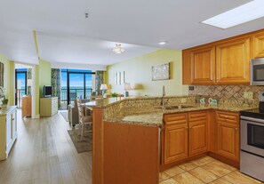 A modern kitchen with wooden cabinets, granite countertops, and a built-in oven. - 3BR Oceanfront Escape w/ Panoramic Views! (Myrtle Beach)