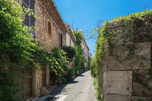Eine enge Straße, gesäumt von Steinhäusern mit Fensterläden und Efeu.